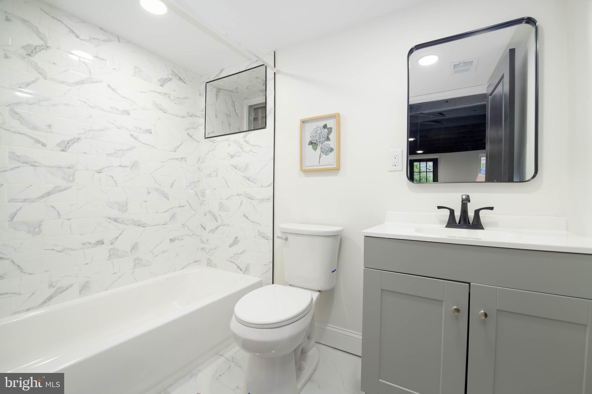 1117 Overbrook Road Baltimore, MD 21239 - Photo 27 of 37 a bathroom with a toilet a sink a mirror a bathtub and shower