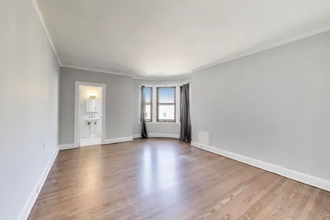 a view of an empty room with window and wooden floor