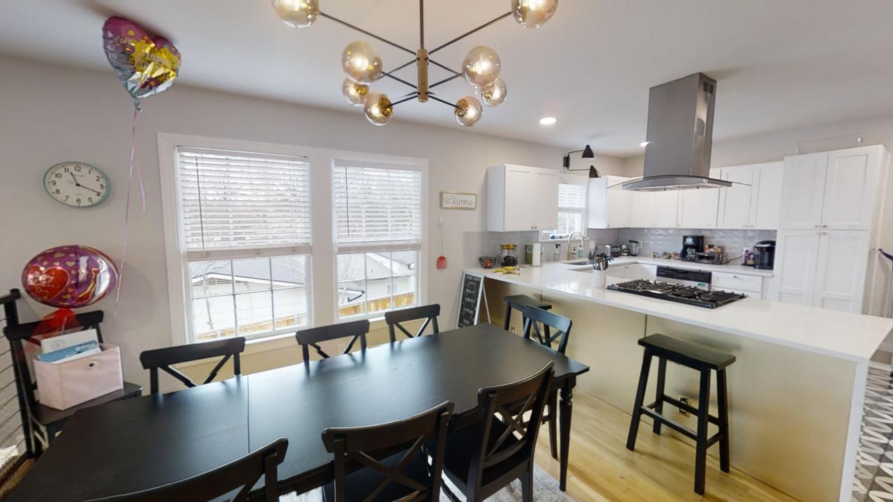 a kitchen with stainless steel appliances granite countertop a stove a refrigerator a kitchen island a dining table and chairs with wooden floor