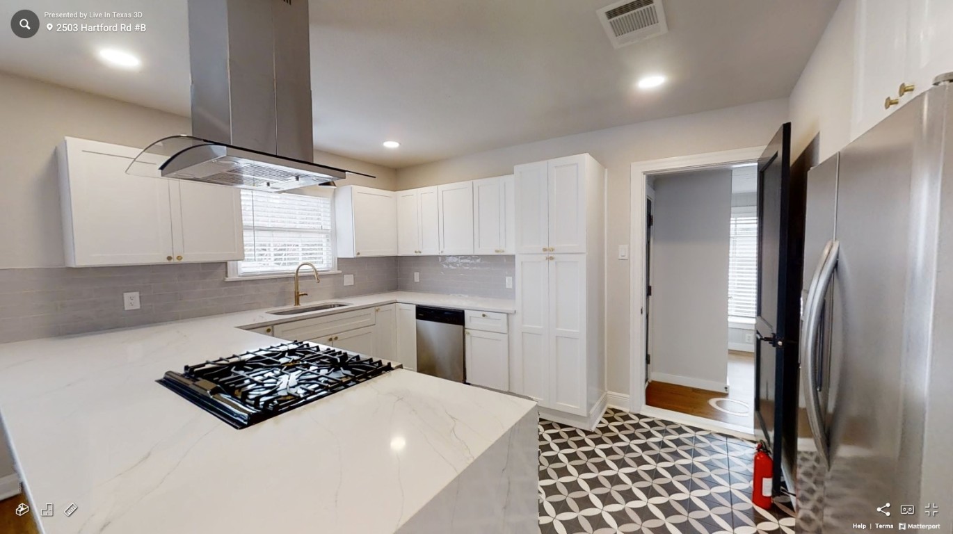 2503 Hartford Road, Unit B Austin, TX 78703 - Photo 4 of 14 Kitchen with appliances with stainless steel finishes, light stone countertops, island exhaust hood, white cabinetry, and tasteful backsplash