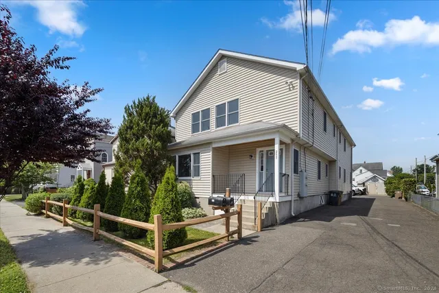 a view of a white house with large windows and a small yard