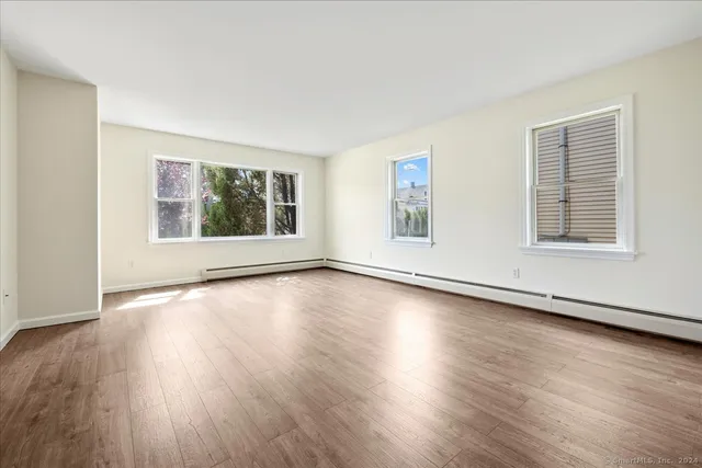 a view of an empty room with wooden floor and windows