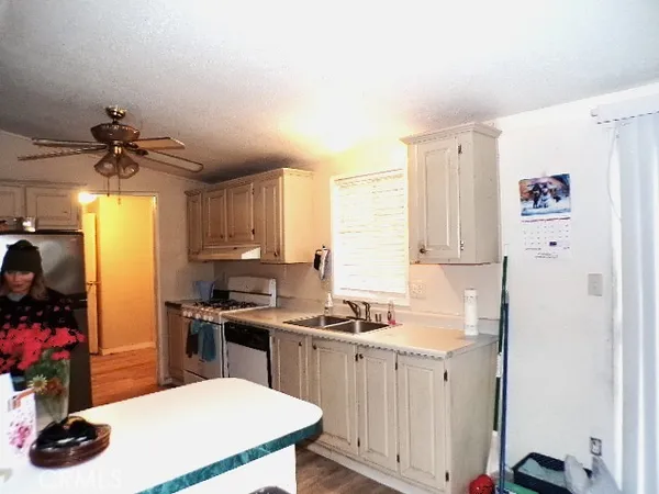 a kitchen with a refrigerator a sink dishwasher and white cabinets with wooden floor