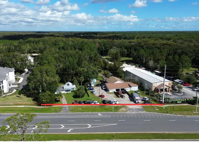 an aerial view of multi story residential apartment building with garage and large trees