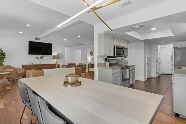 a kitchen with stainless steel appliances granite countertop a stove top oven a sink dishwasher a refrigerator and cabinets with wooden floor