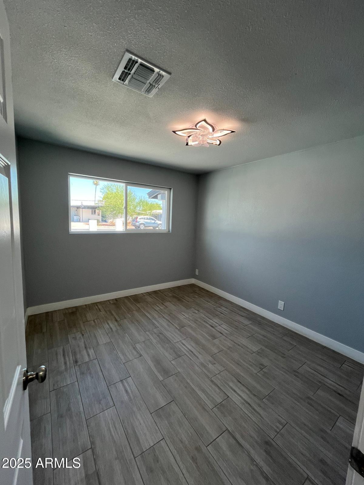 3639 West Lawrence Lane Phoenix, AZ 85051 - Photo 9 of 28 an empty room with wooden floor and windows