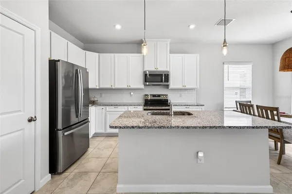 a kitchen with stainless steel appliances granite countertop a refrigerator a sink a stove a microwave and wooden cabinets