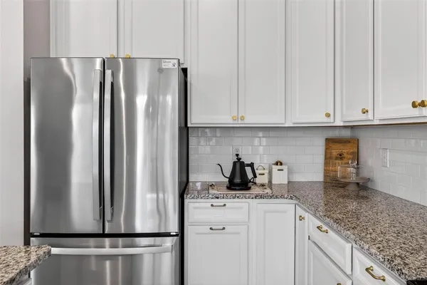 a kitchen with stainless steel appliances granite countertop a refrigerator a white stove and white cabinets