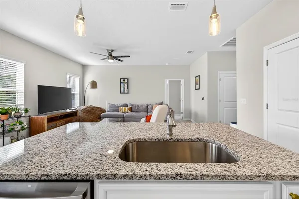 a kitchen with granite countertop a sink a counter top space and cabinets