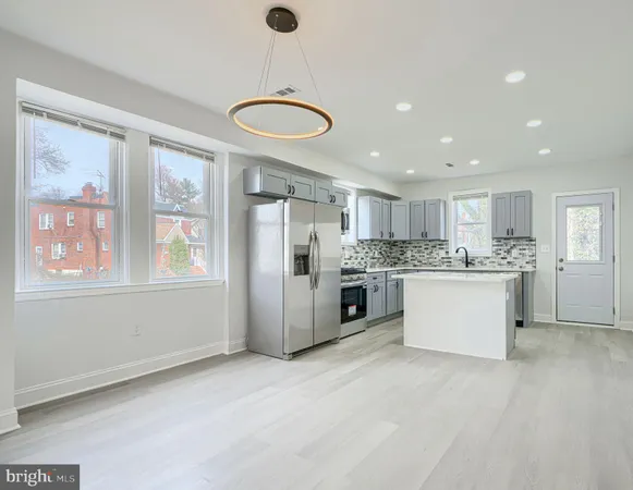 a large kitchen with kitchen island a large counter top space a sink stainless steel appliances and cabinets