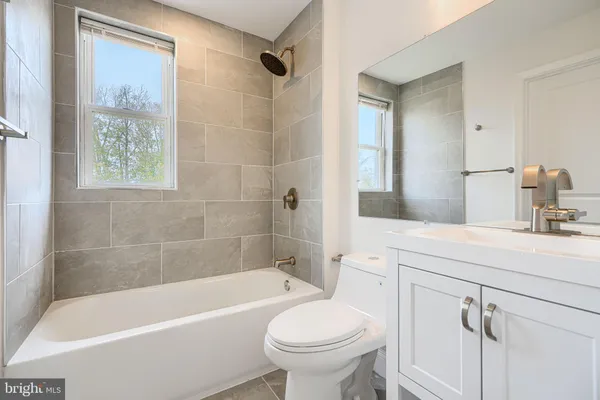 a bathroom with a sink a toilet a mirror a bathtub and shower