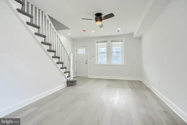 a view of an empty room with wooden floor and stairs
