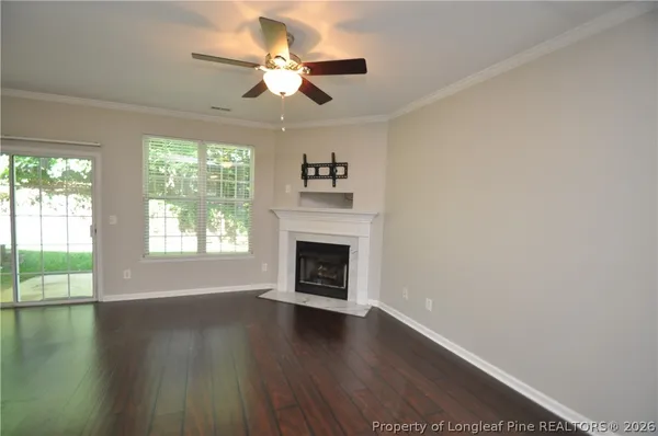 an empty room with wooden floor fireplace and windows