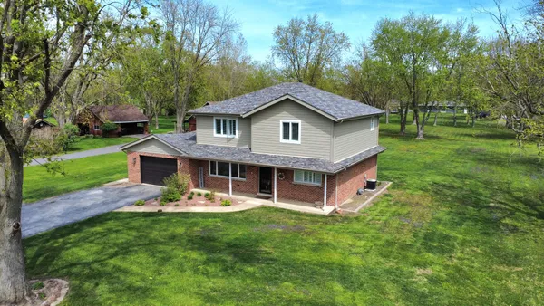 a view of a house with a big yard and large trees