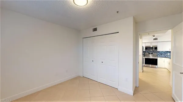 a view of kitchen with refrigerator and white cabinets