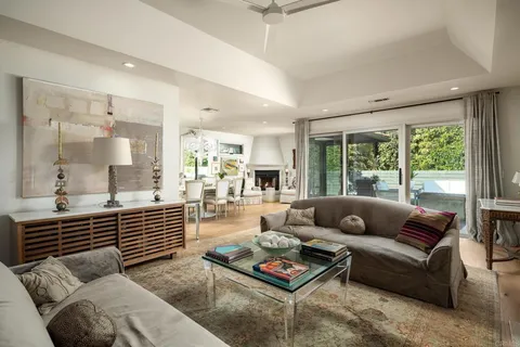 a living room with furniture a rug kitchen view and a large window
