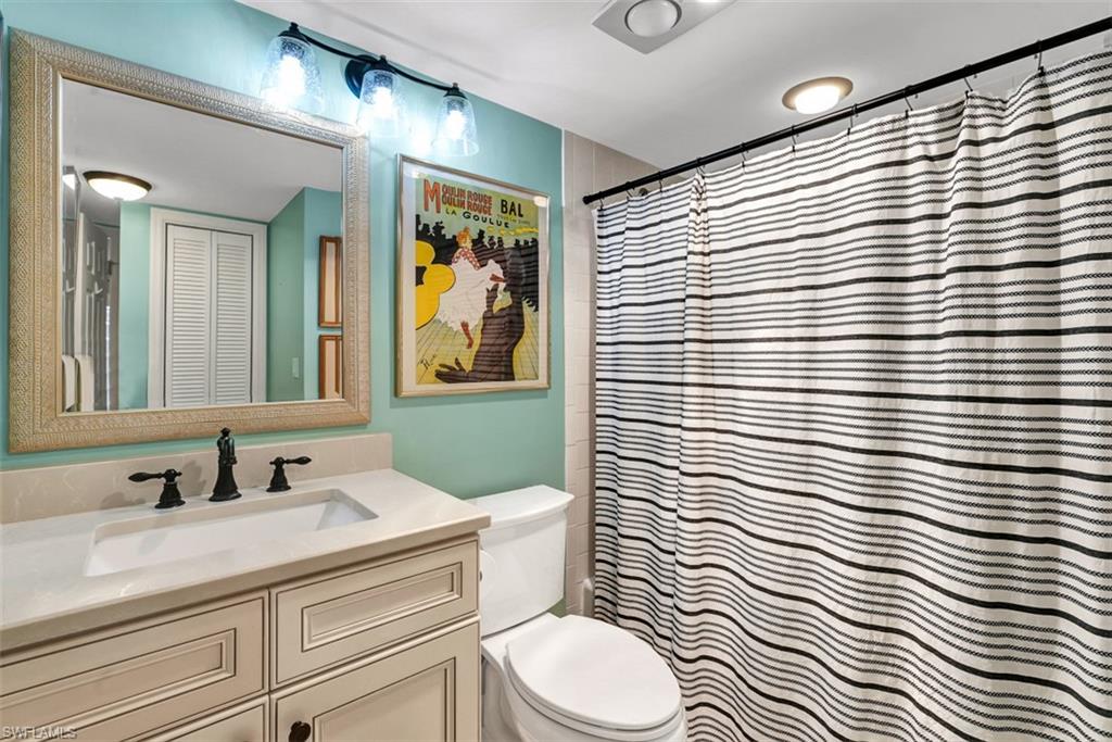 1617 Spoonbill Lane, Unit 1617 Naples, FL 34105 - Photo 15 of 31 a bathroom with a sink a toilet a mirror and shower curtain