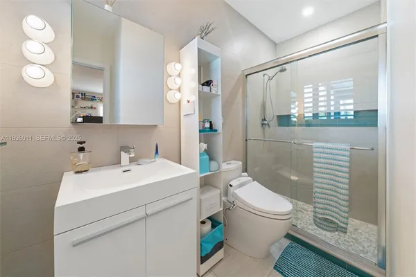 a bathroom with a sink a toilet a mirror and shower