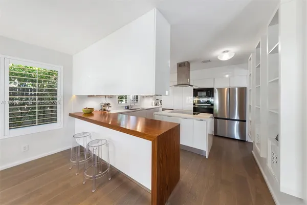 a kitchen with stainless steel appliances granite countertop a sink a stove a refrigerator and island with wooden floor