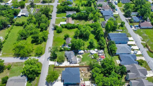 an aerial view of residential houses with outdoor space and trees