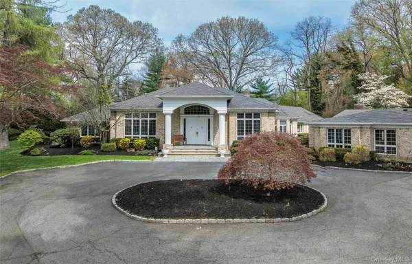 a front view of a house with a garden and trees
