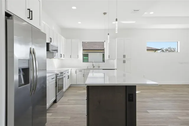 a kitchen with stainless steel appliances granite countertop a sink a refrigerator and a stove