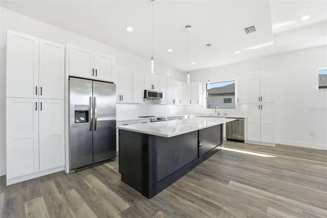 a kitchen with kitchen island a sink stainless steel appliances and refrigerator