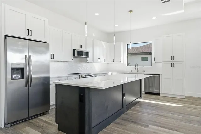 a kitchen with kitchen island a sink appliances and cabinets