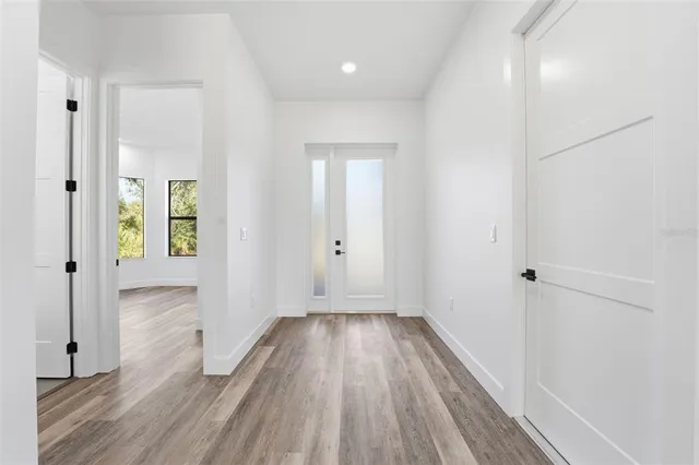 a view of a hallway with wooden floor and a bathroom