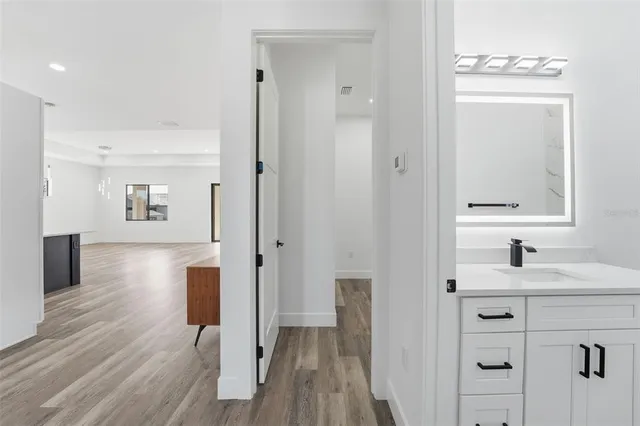 a view of a hallway with wooden floor windows and a bathroom