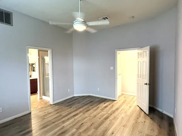 a view of empty room with wooden floor and fan