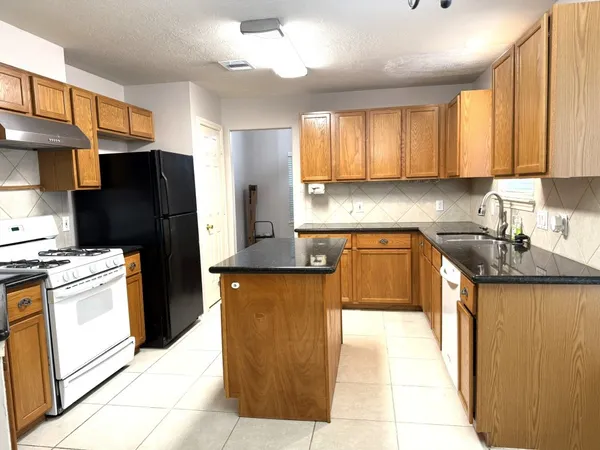 a kitchen with stainless steel appliances granite countertop a refrigerator a stove and a sink