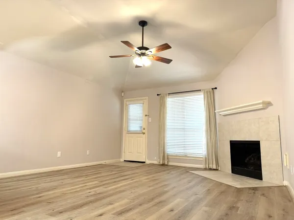 an empty room with chandelier fan and windows
