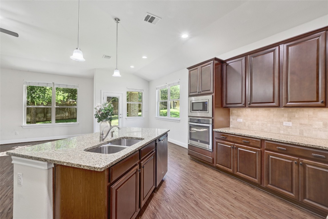 a kitchen with stainless steel appliances granite countertop a sink a stove and a wooden floors