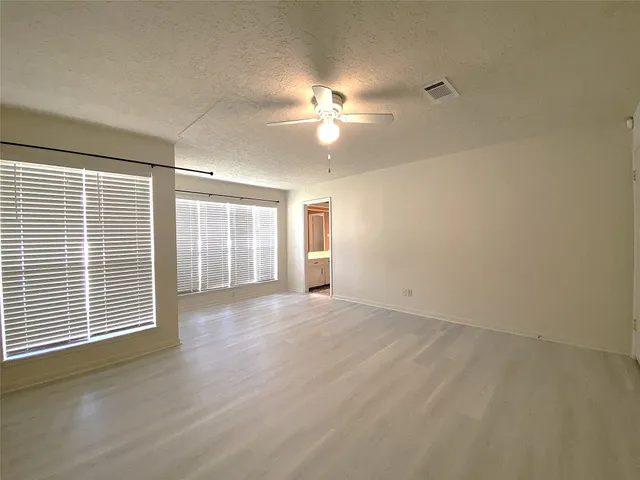 en empty room with windows and ceiling fan