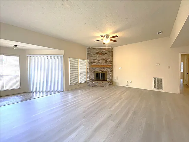 a view of empty room with wooden floor and fireplace