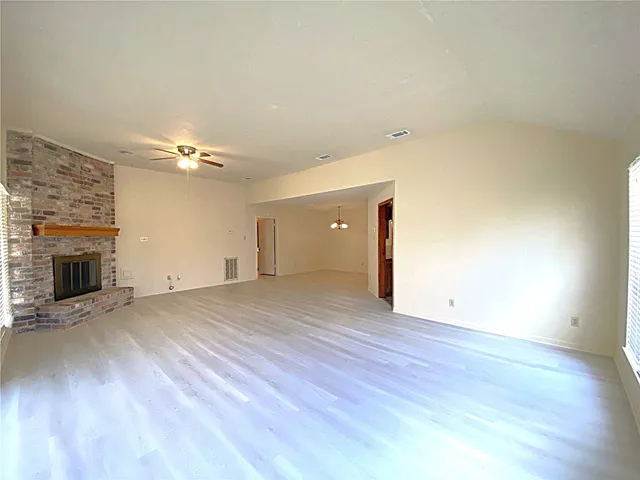 a view of an empty room with wooden floor and a fireplace