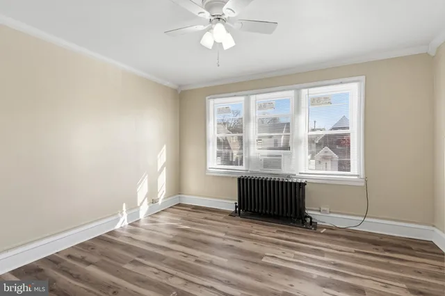 an empty room with wooden floor fan and windows