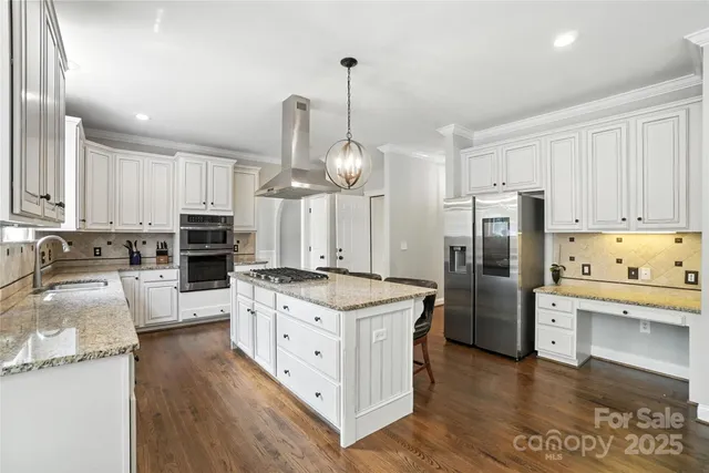 a kitchen with stainless steel appliances granite countertop a refrigerator a stove and a wooden floors