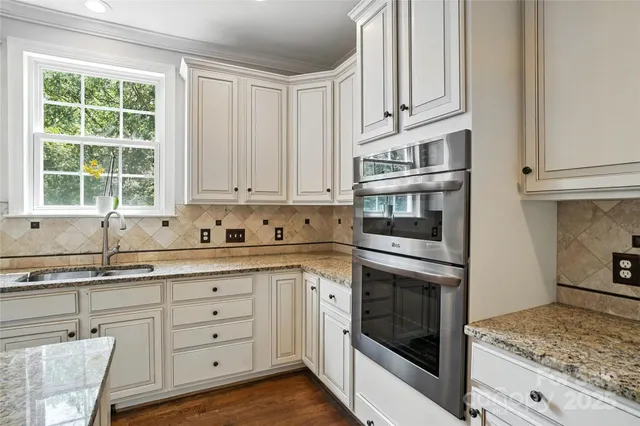 a kitchen with granite countertop white cabinets and stainless steel appliances