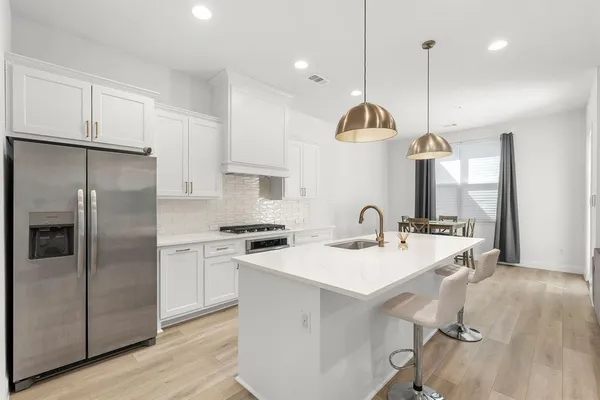 a kitchen with stainless steel appliances granite countertop a sink a stove a refrigerator cabinets and chairs