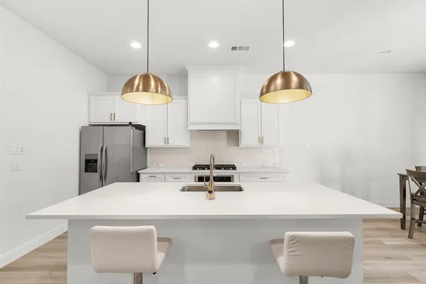 a kitchen with a sink a refrigerator and chairs