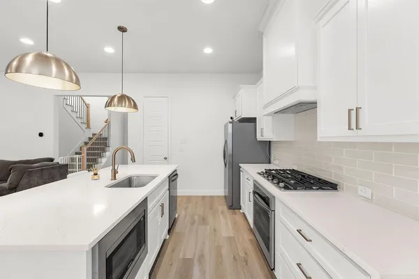 a kitchen with kitchen island stainless steel appliances a sink a stove and a wooden floor