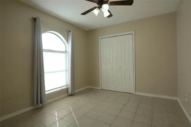 an empty room with a window and a chandelier fan