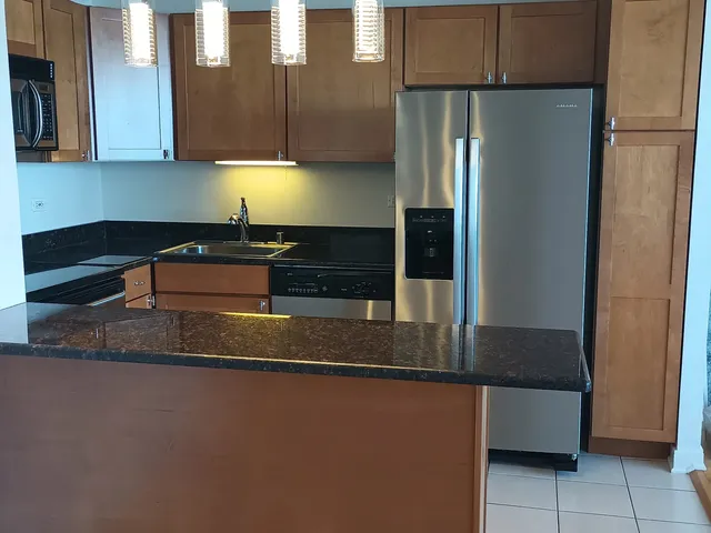 a kitchen with stainless steel appliances granite countertop a refrigerator a stove and a sink with wooden floor