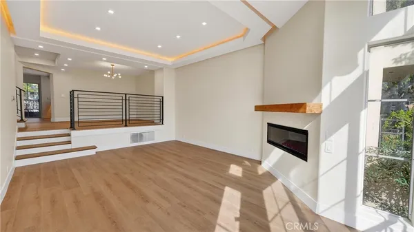 a view of an empty room with wooden floor and a kitchen