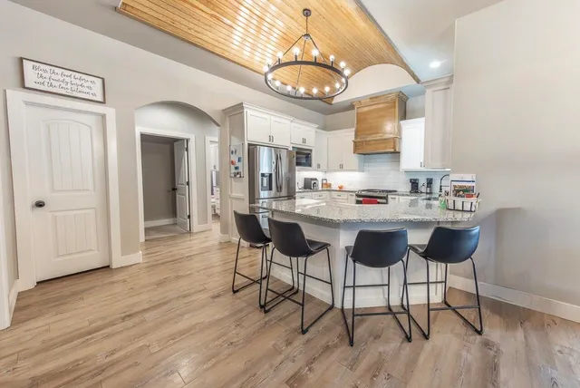 a kitchen with stainless steel appliances kitchen island granite countertop a table and chairs in it