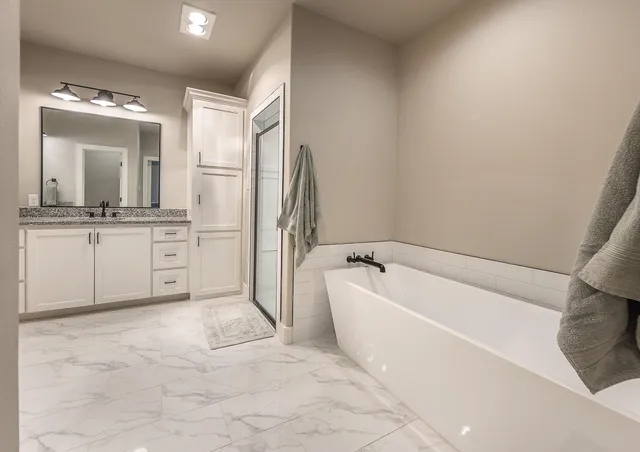 a bathroom with a bathtub a mirror a shower and vanity