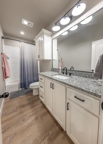 a bathroom with a granite countertop sink mirror and a toilet
