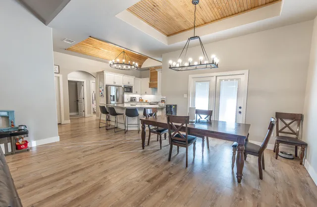 a dining room with wooden floor a chandelier a wooden table and chairs